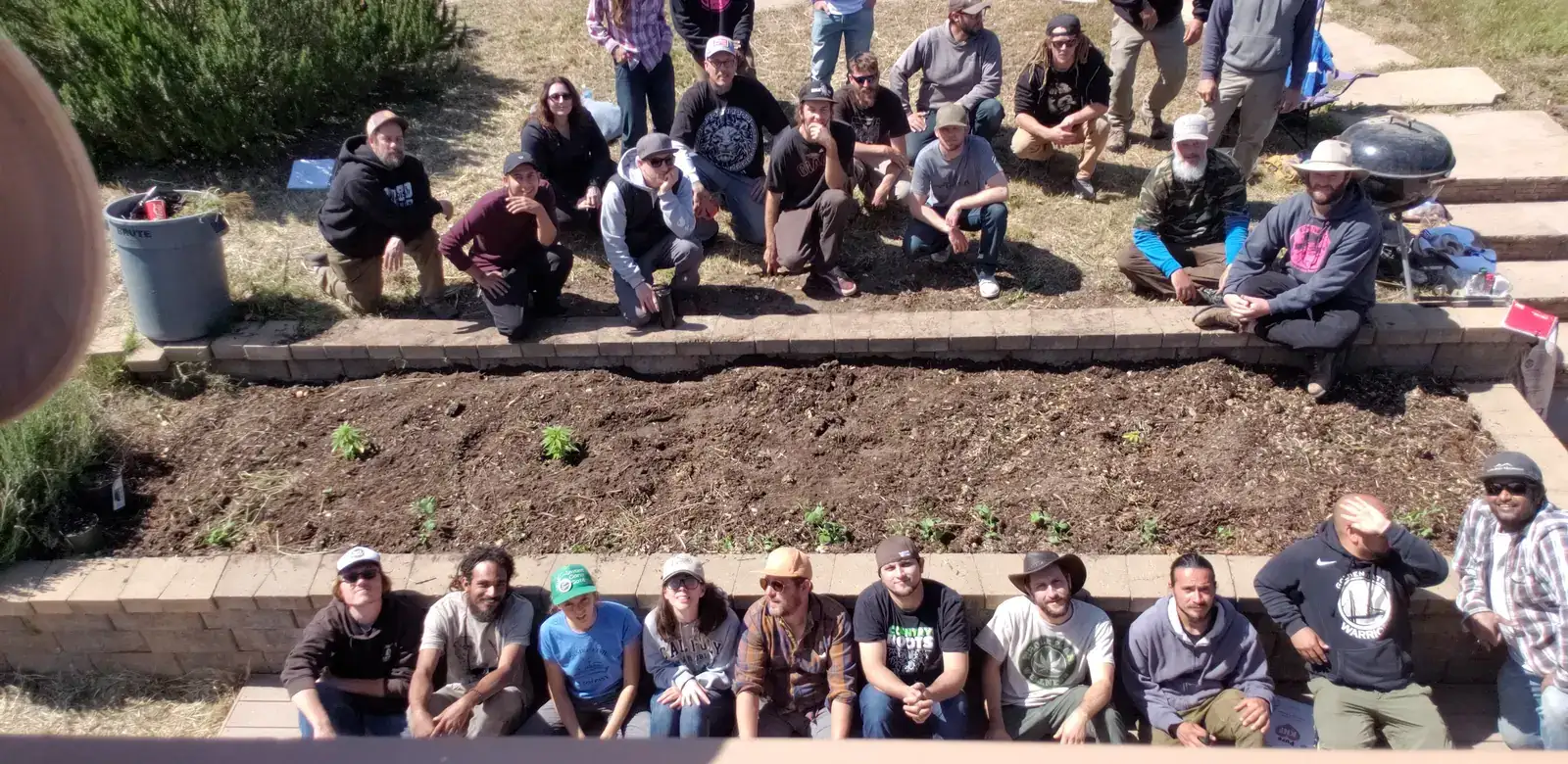 About thirty growers posing in two rows around a freshly planted raised bed